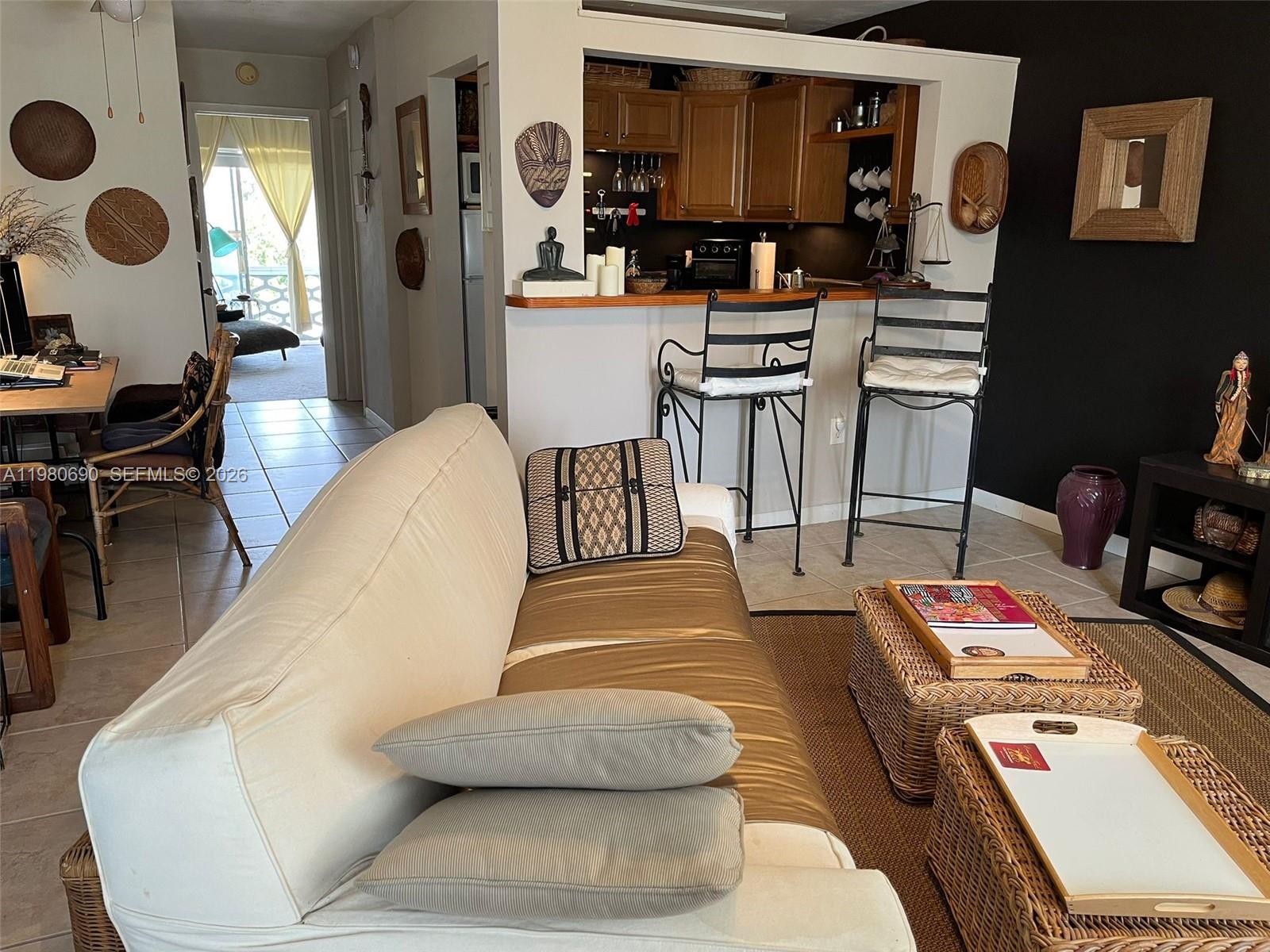 A living room with a sofa, wicker coffee tables, and a kitchen breakfast bar — 15610 NE 6th Ave # 19C, Miami FL 33162, MIAMI, FL