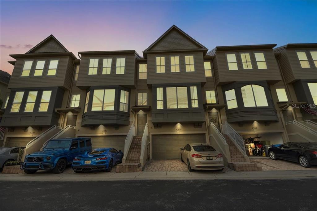 A row of three-story townhouses with attached garages and parked cars in the driveway — 4336 SPINNAKER COVE LANE, TAMPA, FL