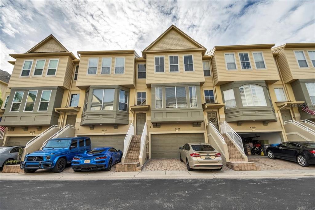 A row of multi-story townhouses with attached garages and parked cars in the driveway — 4336 SPINNAKER COVE LANE, TAMPA, FL