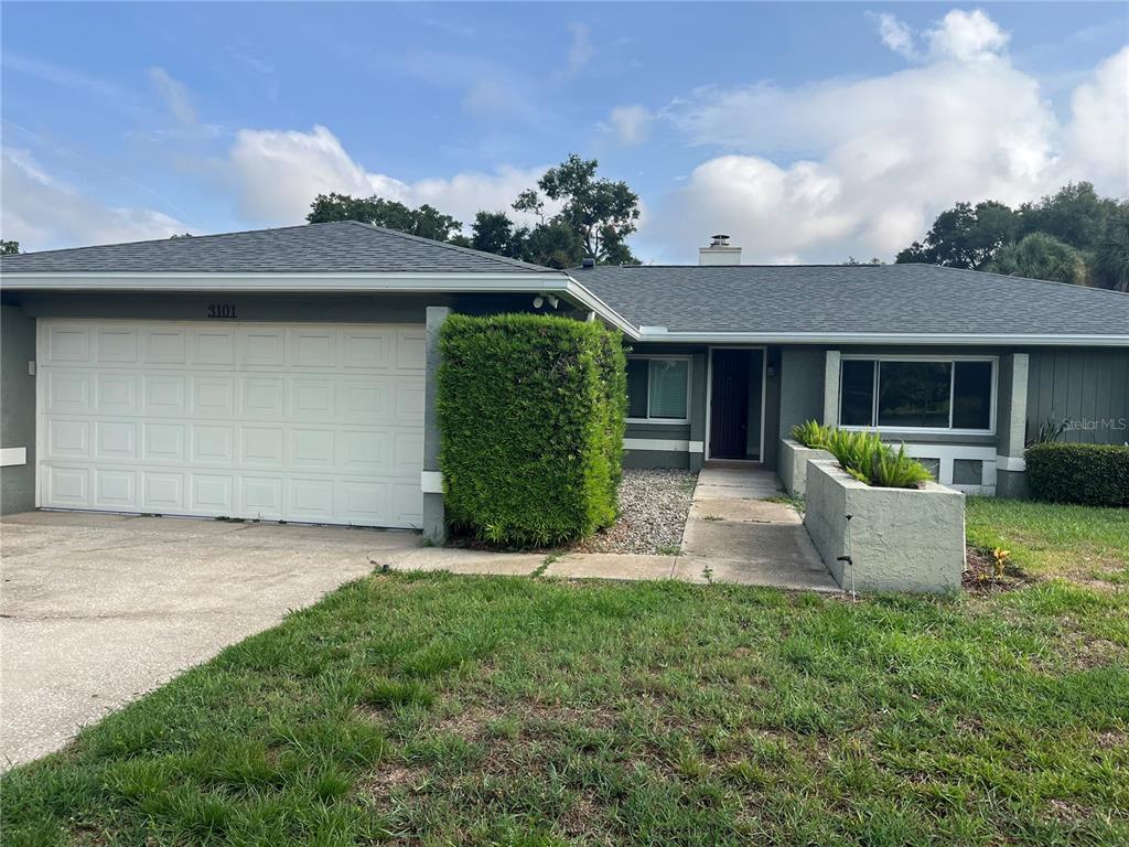 A single-story house with a gray exterior, a two-car garage, and a front walkway — 3101 VILLAGE LANE, MOUNT DORA, FL