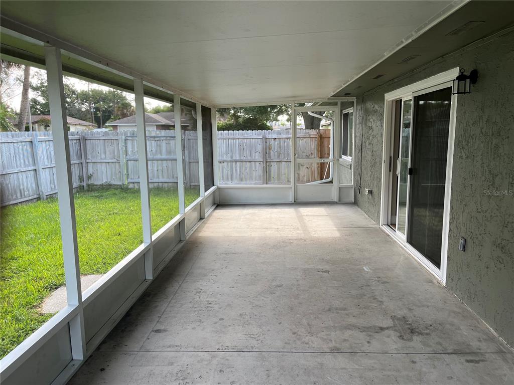 A screened-in porch features a concrete floor, white framing, and a sliding glass door — 3101 VILLAGE LANE, MOUNT DORA, FL