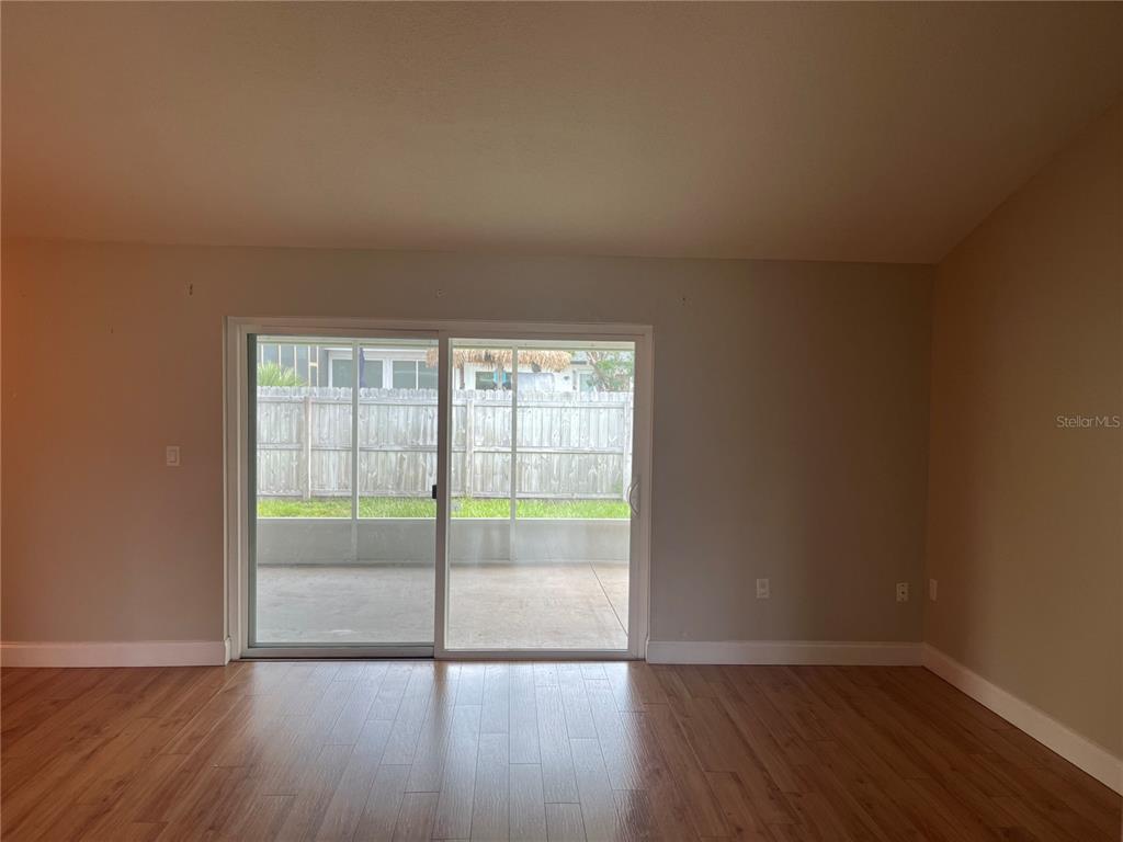 An empty room features light-colored walls, wood-look flooring, and a doorway leading to a hallway — 3101 VILLAGE LANE, MOUNT DORA, FL