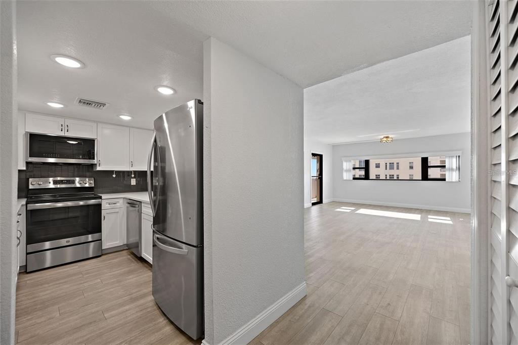 A kitchen with stainless steel appliances opens into a bright, empty living area with flooring — 4141 BAYSHORE BOULEVARD UNIT 1702, TAMPA, FL