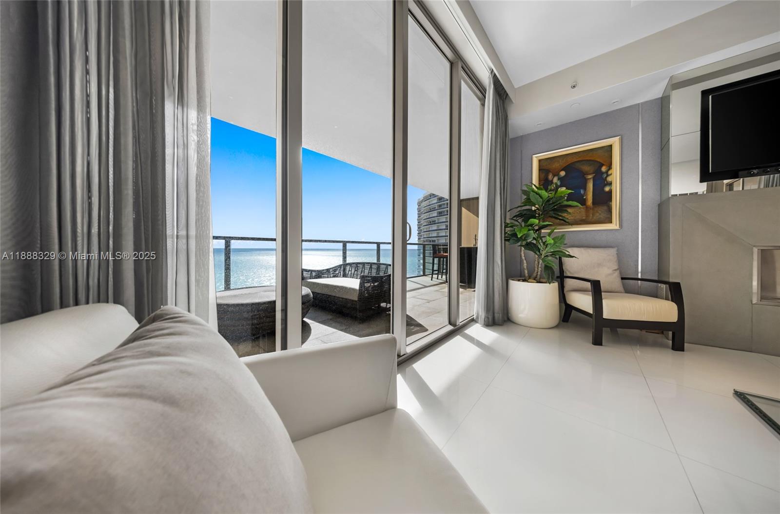 A living room with white tile floors, floor-to-ceiling windows, and a balcony overlooking the ocean — 9701 Collins Avenue, Bal Harbour FL 33154, BAL HARBOUR, FL