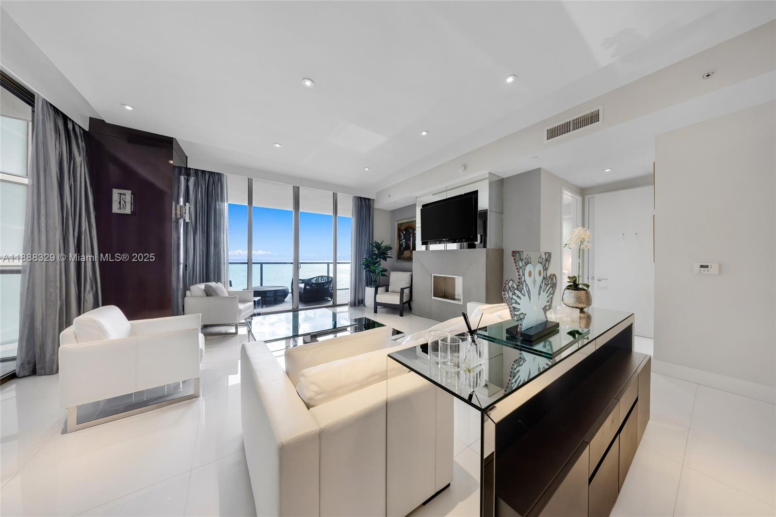 A modern living room features white leather furniture, a glass coffee table, and ocean views — 9701 Collins Avenue, Bal Harbour FL 33154, BAL HARBOUR, FL