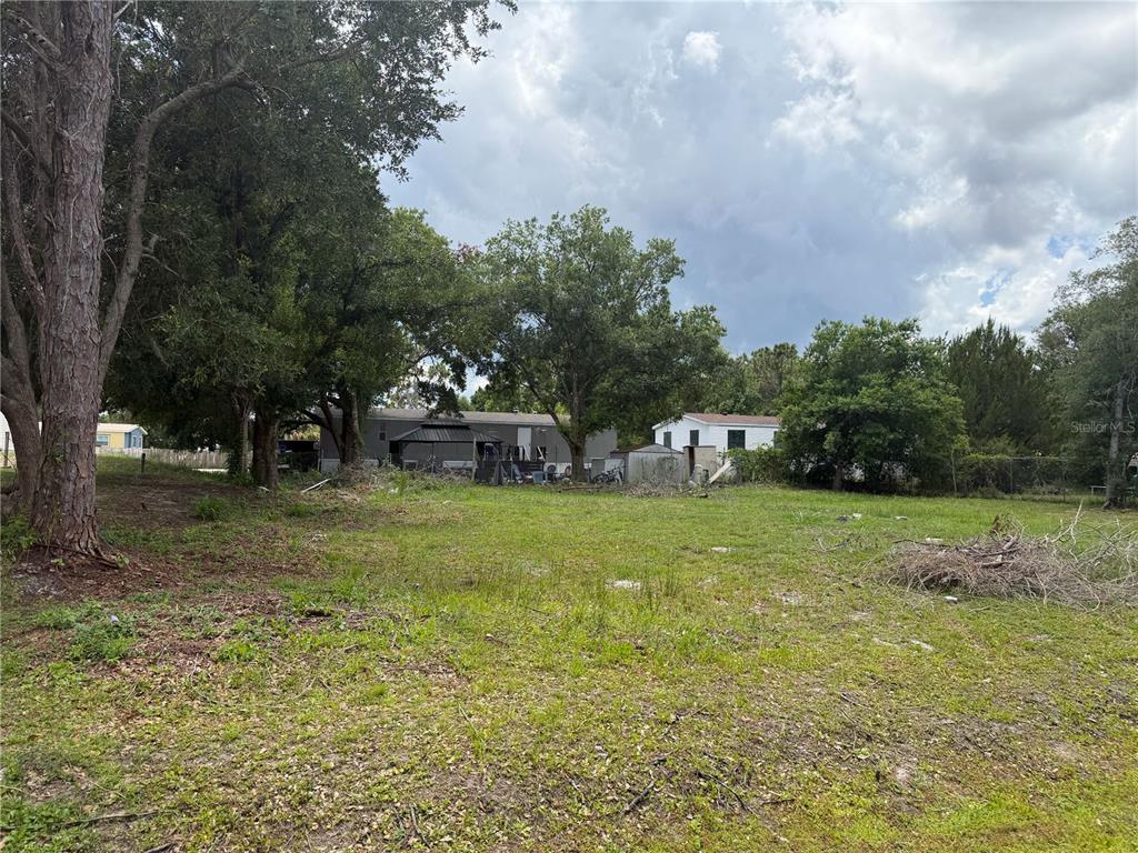A vacant, grassy lot with scattered trees and neighboring houses in the background — 15TH AVENUE, ORLANDO, FL
