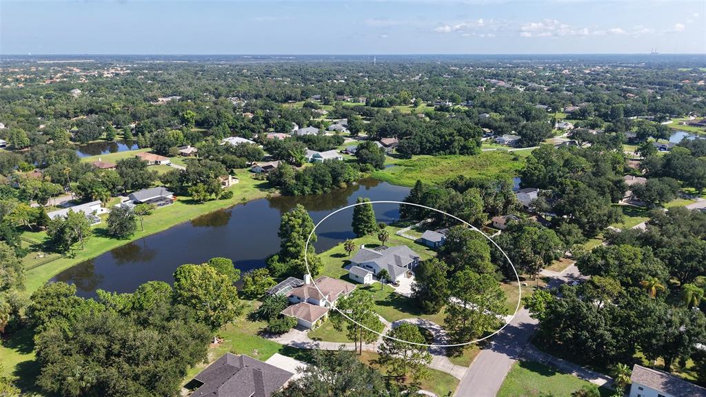 An aerial view shows a house with a circular driveway situated beside a large pond — 602 137TH STREET E, BRADENTON, FL