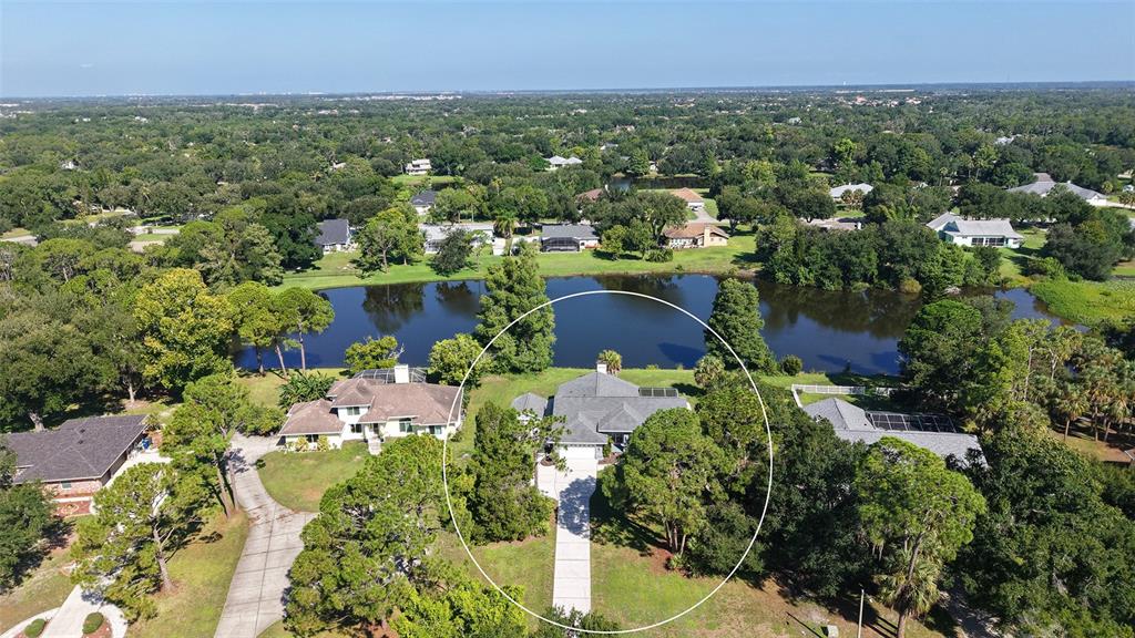 An aerial view shows a house with a driveway situated next to a lake — 602 137TH STREET E, BRADENTON, FL