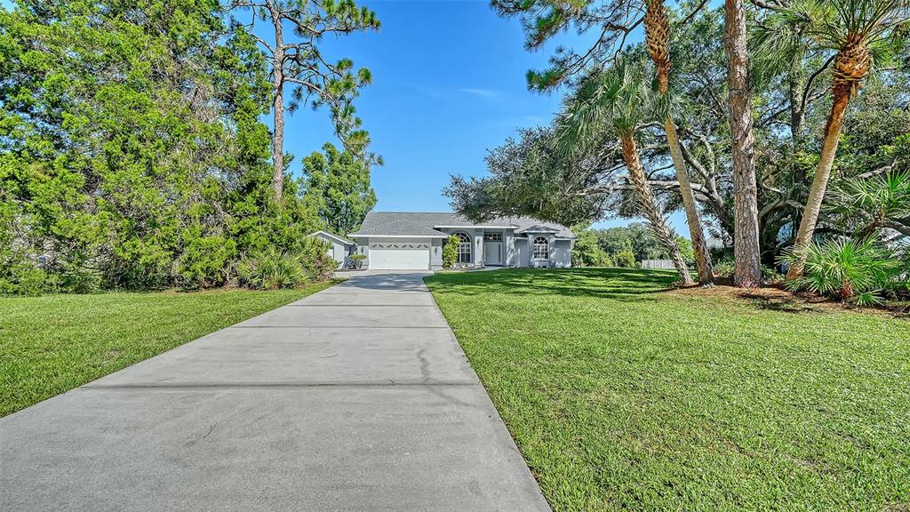 A single-story house with a concrete driveway and a large front lawn under blue skies — 602 137TH STREET E, BRADENTON, FL
