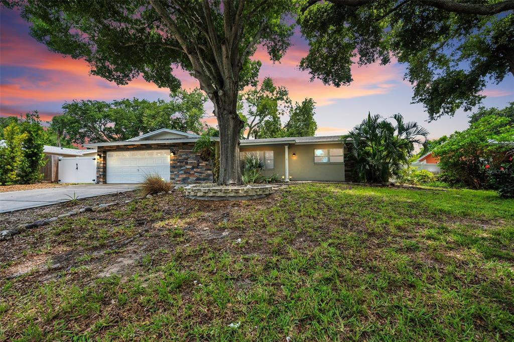 A single-story house with a stone-accented garage and a large tree in the front yard — 13760 87TH PLACE, SEMINOLE, FL