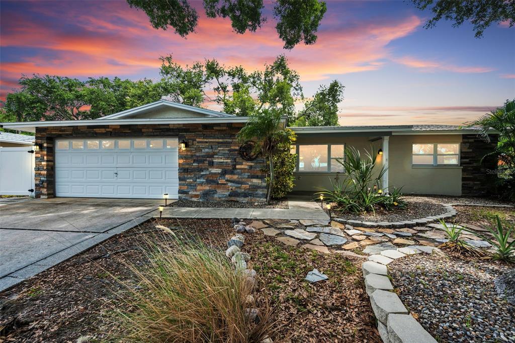 A single-story house with a stone facade, white garage door, and a landscaped front yard — 13760 87TH PLACE, SEMINOLE, FL