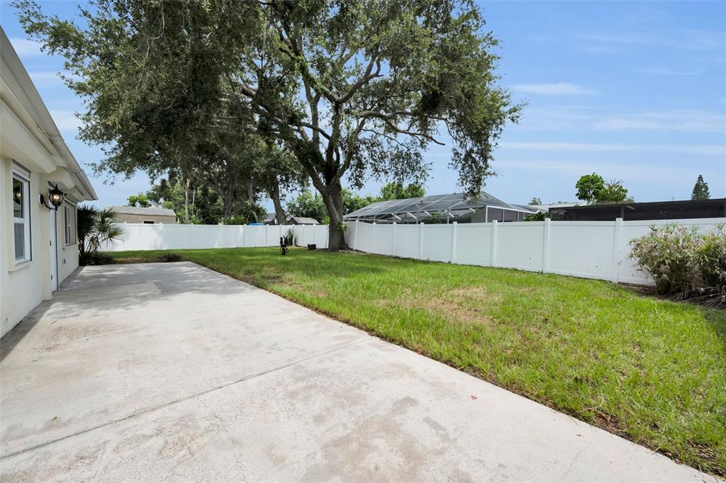 A concrete patio extends from the side of a house into a fenced grassy backyard — 13760 87TH PLACE, SEMINOLE, FL