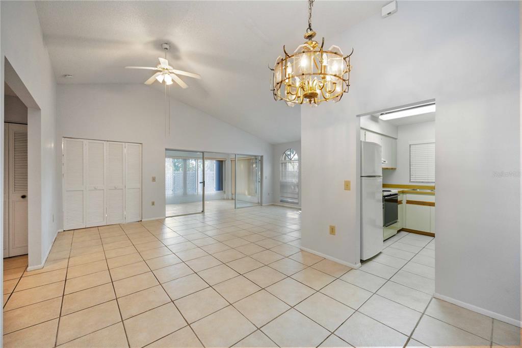 A tiled living area with a vaulted ceiling, ceiling fan, chandelier, and adjacent kitchen — 3411 57TH AVENUE DRIVE W UNIT 6, BRADENTON, FL
