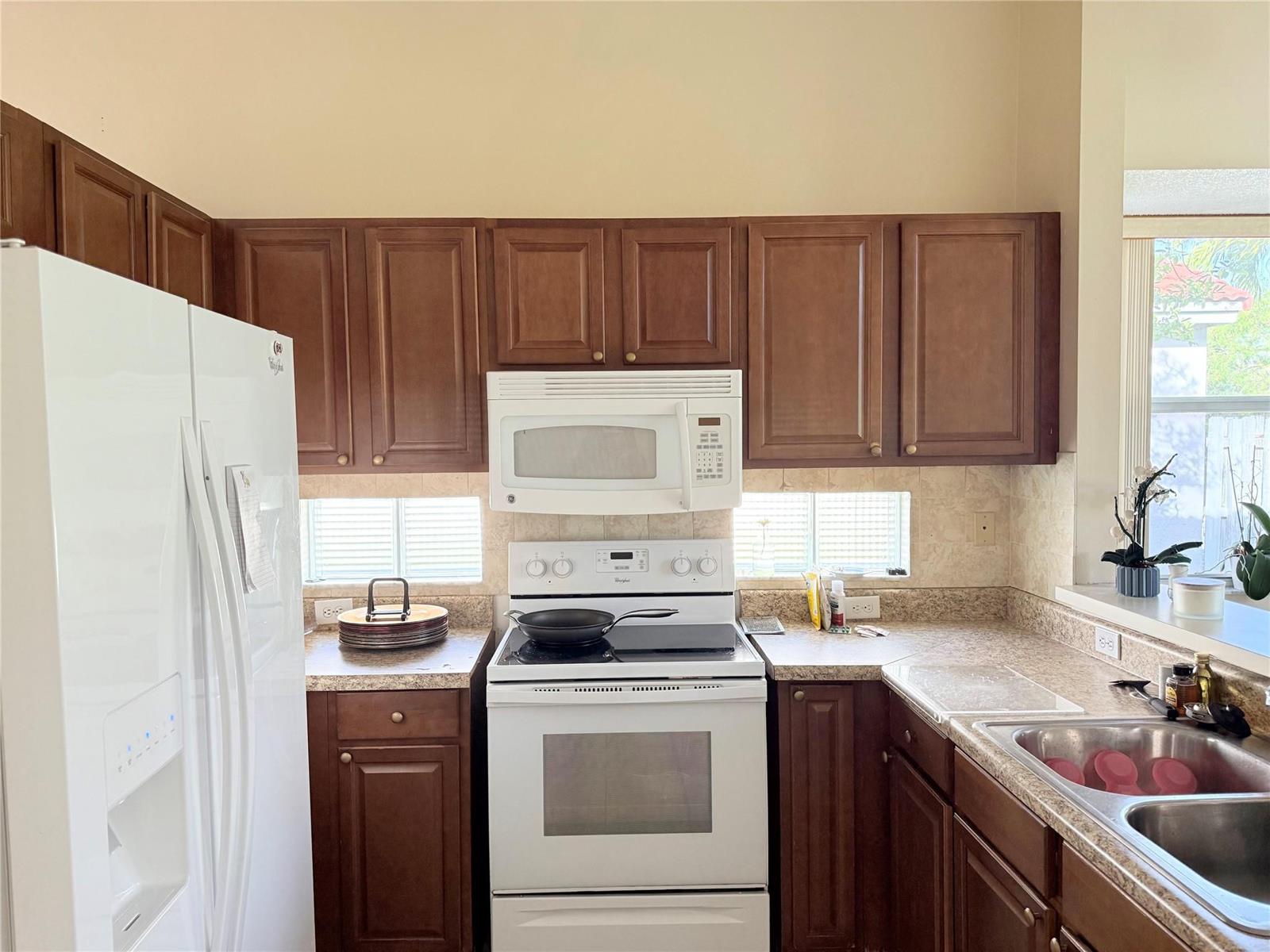 A kitchen features dark wood cabinets, white appliances, a tiled backsplash, and a double sink — 4965 SW 153rd Avenue, Davie FL 33331, DAVIE, FL