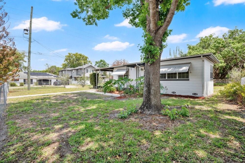 A white single-story house with a metal awning stands behind a large tree in a yard — 2501 BETHAWAY AVENUE, ORLANDO, FL