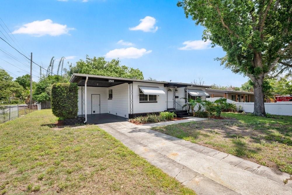 A single-story house with white siding, a carport, and a concrete driveway under a tree — 2501 BETHAWAY AVENUE, ORLANDO, FL