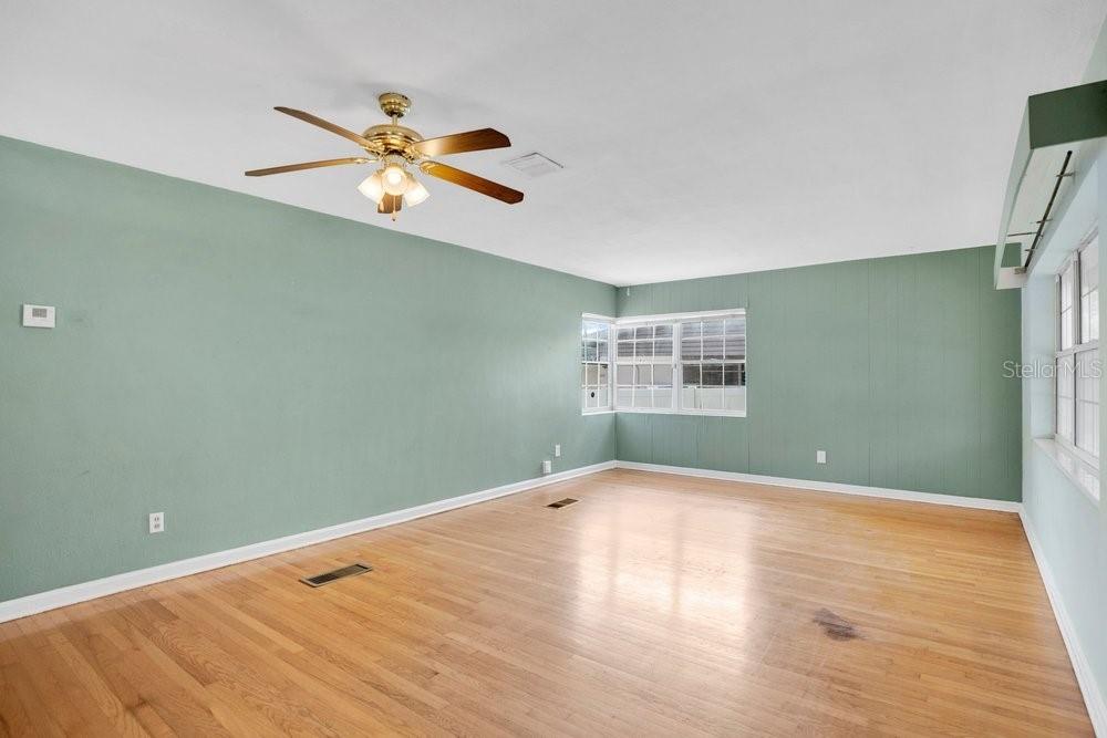 An empty room features light green paneled walls, hardwood floors, and a ceiling fan — 2501 BETHAWAY AVENUE, ORLANDO, FL