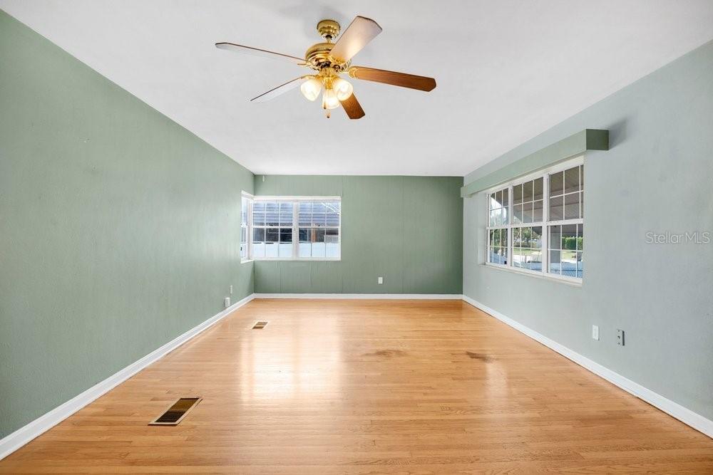 An empty room features light wood flooring, sage green walls, and a ceiling fan — 2501 BETHAWAY AVENUE, ORLANDO, FL