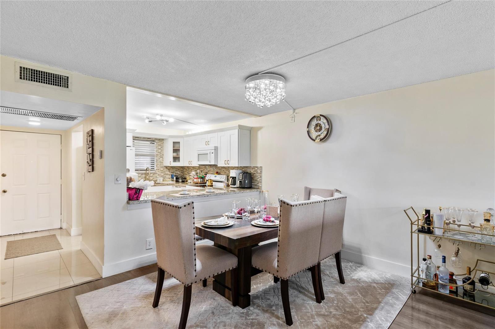 A dining area features a wooden table with four upholstered chairs beneath a crystal chandelier — 9300 SW 8th Street # 102, Boca Raton FL 33428, BOCA RATON, FL