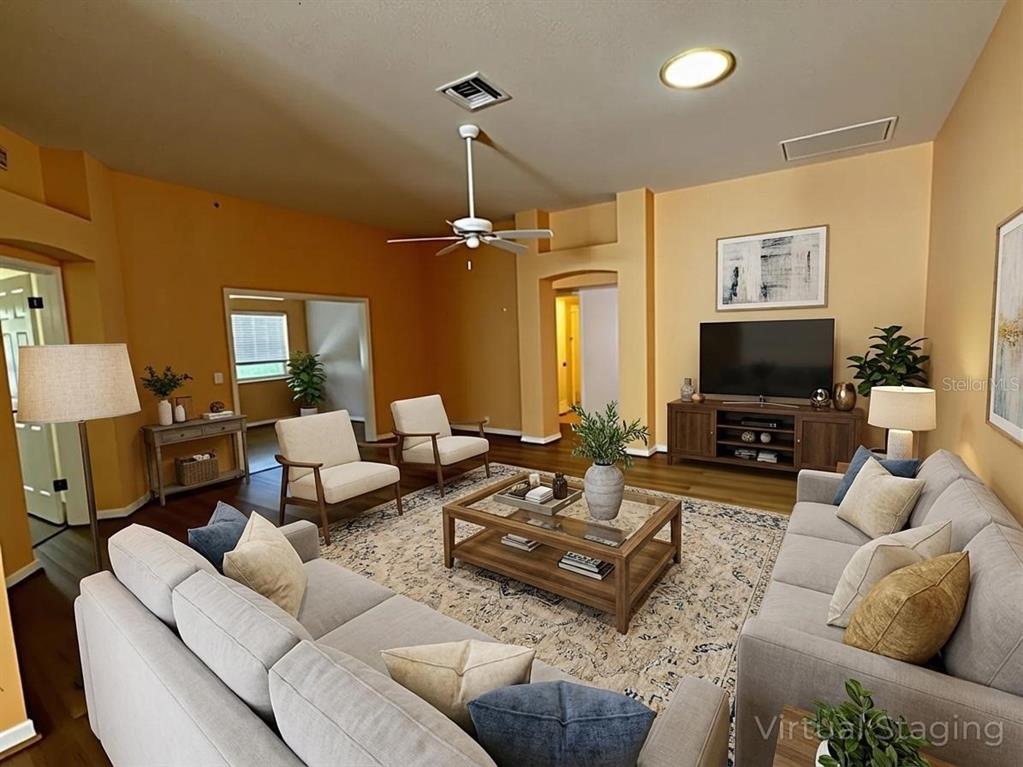 A living room with light-colored sofas, armchairs, a coffee table, and a television on a console — 144 COSTA MESA DRIVE, LADY LAKE, FL
