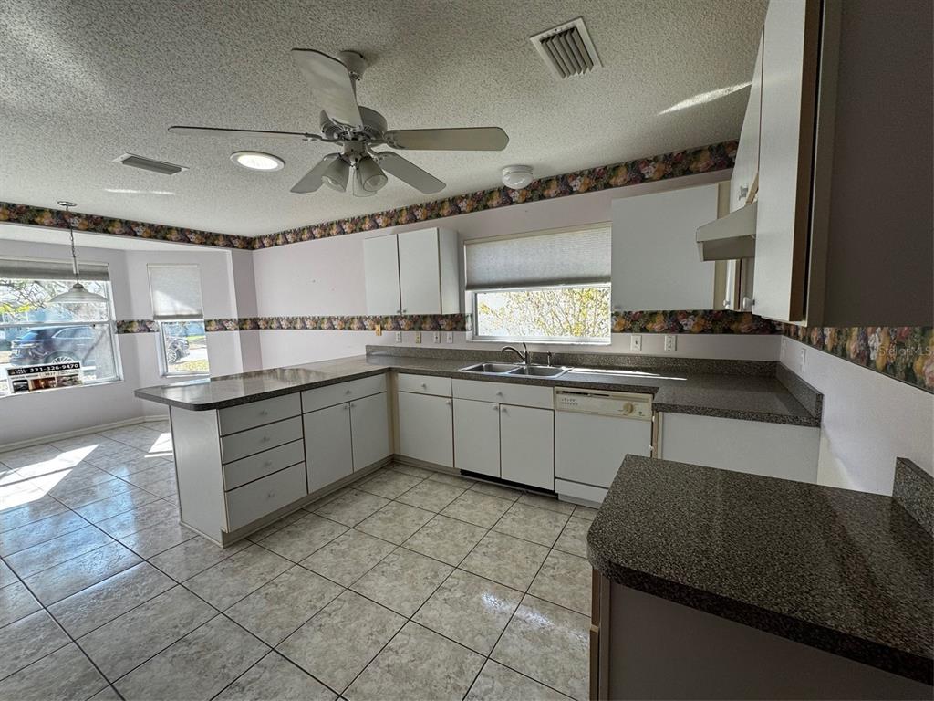 A kitchen with white cabinets, granite-look countertops, tile flooring, and a ceiling fan — 144 COSTA MESA DRIVE, LADY LAKE, FL