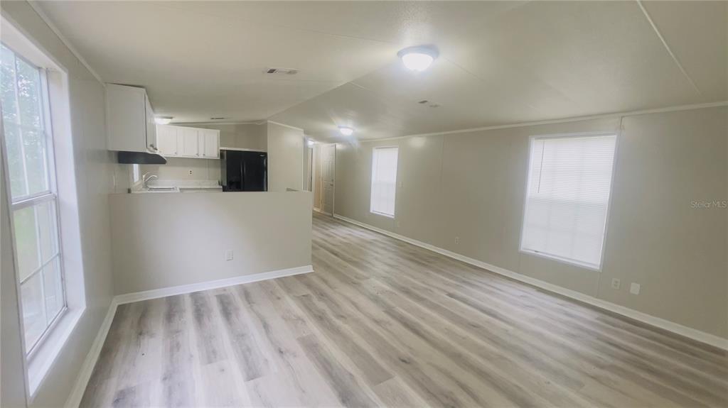 An open-concept living area features light-colored wood-look flooring, neutral walls, and a kitchen pass-through — 4053 NE 213TH TERRACE, WILLISTON, FL