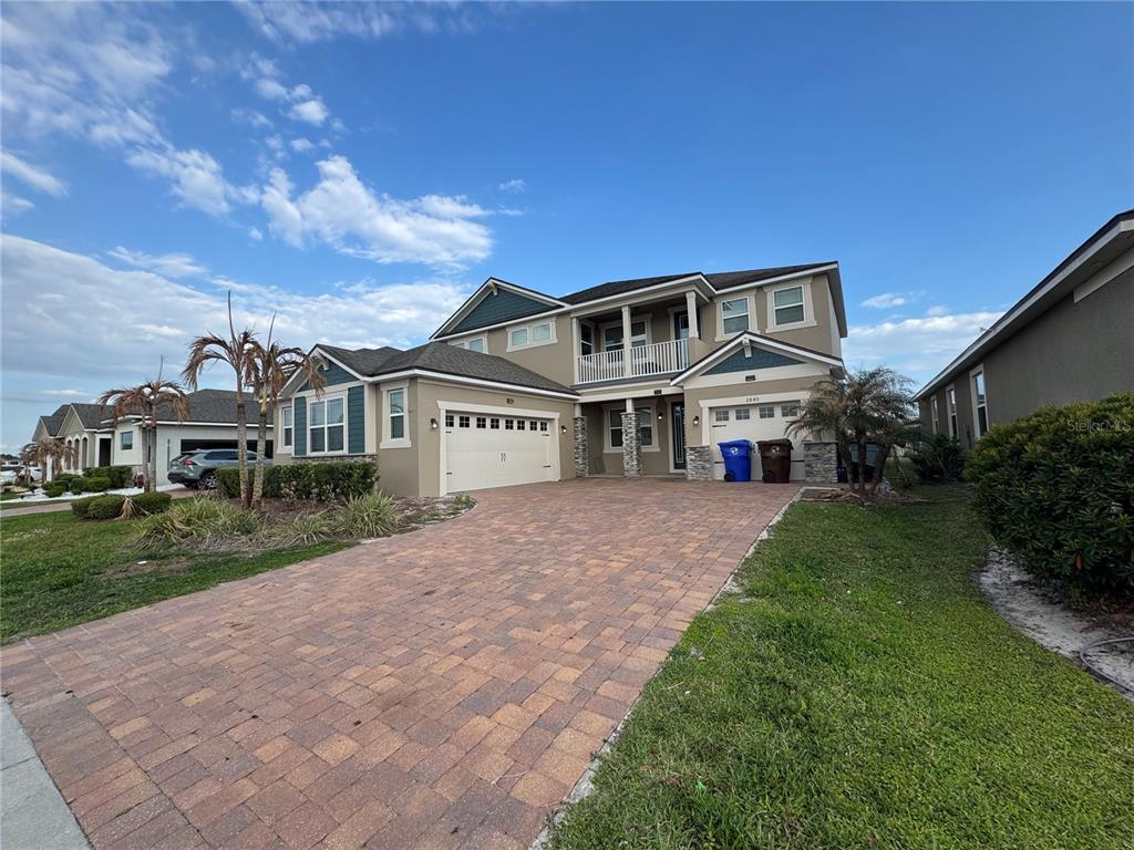 A two-story suburban house features a paved driveway, a three-car garage, and a balcony — 2840 CHANTILLY AVENUE, KISSIMMEE, FL