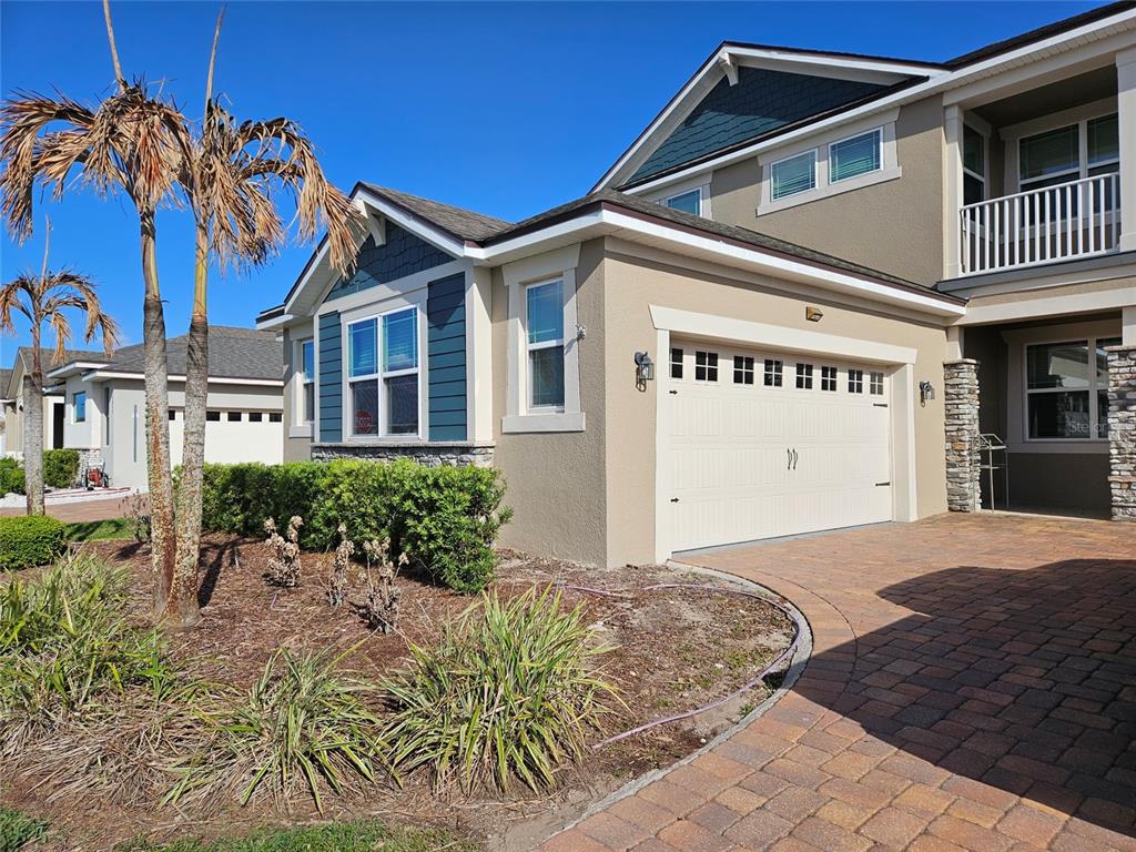 A two-story suburban house features a beige stucco exterior, a two-car garage, and landscaping — 2840 CHANTILLY AVENUE, KISSIMMEE, FL