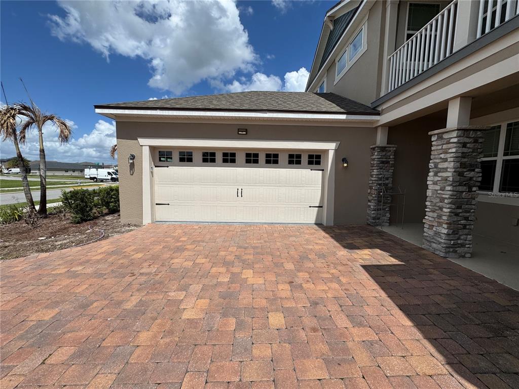 A beige garage door with windows sits above a brick paver driveway — 2840 CHANTILLY AVENUE, KISSIMMEE, FL