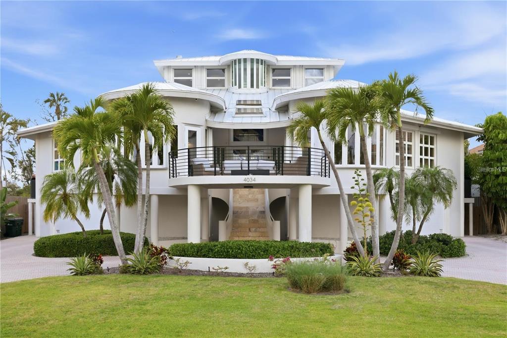 A multi-story coastal home with a raised balcony, metal roof, and palm trees in front — 4034 ROBERTS POINT ROAD, SARASOTA, FL