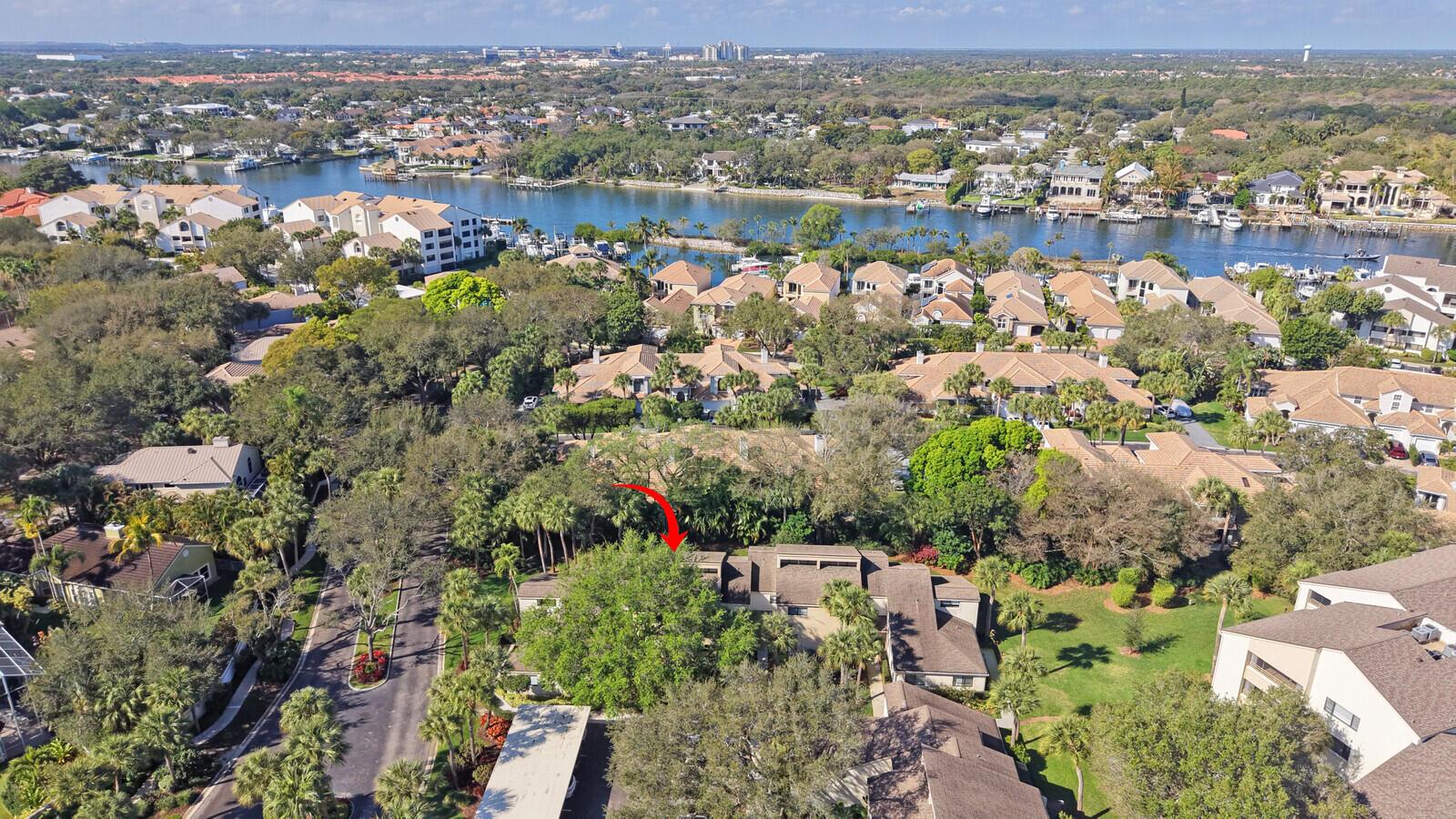 An aerial view shows a residential complex surrounded by lush trees near a waterway — 215 Oak Harbour Drive, Juno Beach FL 33408, JUNO BEACH, FL