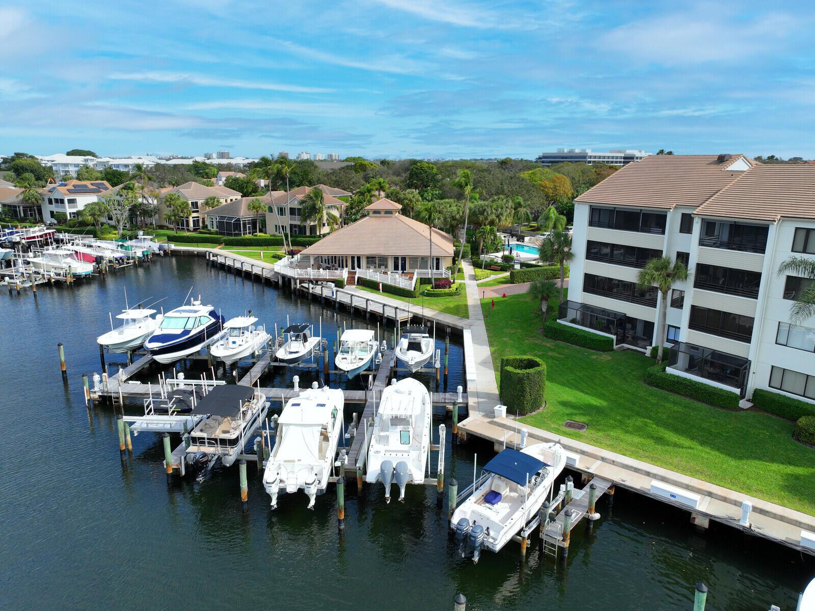 An aerial view shows a marina with docked boats next to a multi-story apartment building — 215 Oak Harbour Drive, Juno Beach FL 33408, JUNO BEACH, FL