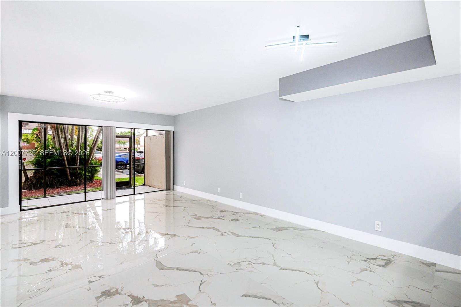 An empty room features light gray walls, white marble-patterned tile flooring, and a sliding glass door — 7111 SW 42nd Pl, Davie FL 33314, DAVIE, FL