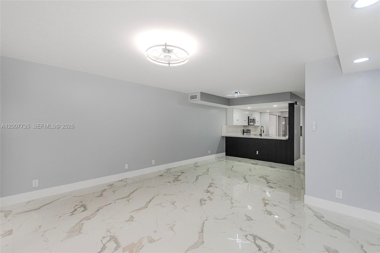 An open-concept living area features gray walls, white marble-patterned tile floors, and a kitchen peninsula — 7111 SW 42nd Pl, Davie FL 33314, DAVIE, FL
