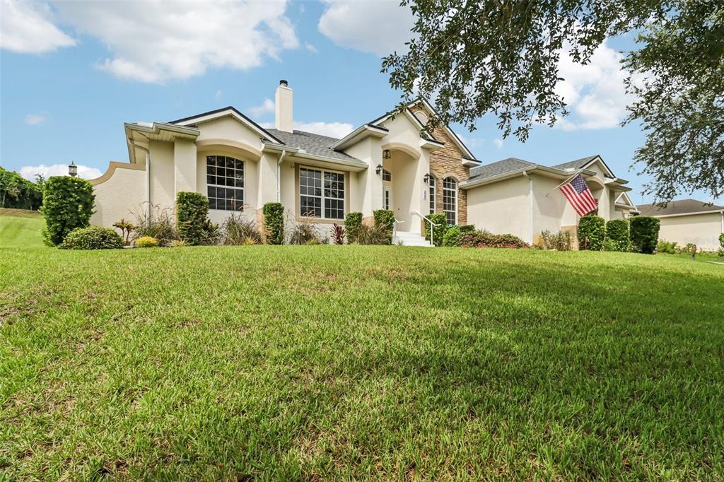A single-story house with a beige stucco exterior, stone accents, and a front lawn — 225 GLEN ABBEY LANE, DEBARY, FL