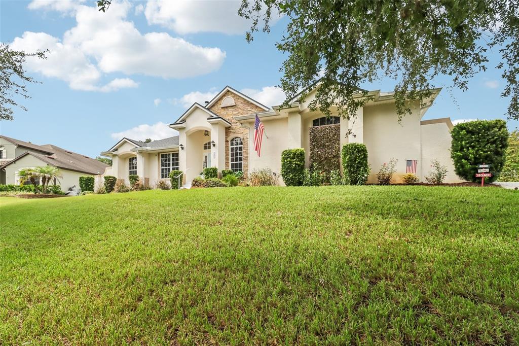 A single-story house with a stucco exterior, stone accents, and a large front lawn — 225 GLEN ABBEY LANE, DEBARY, FL