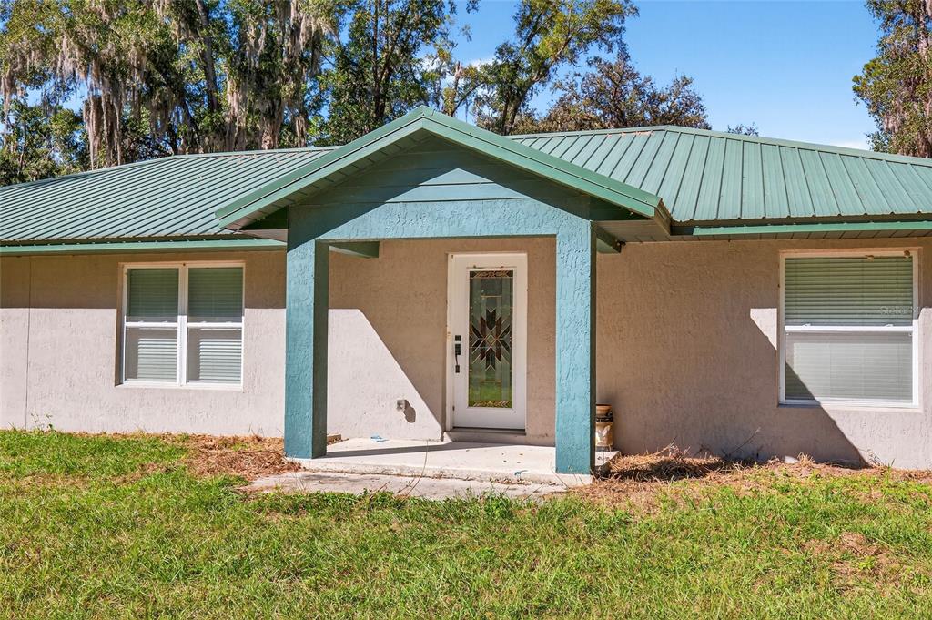 A single-story house with a green metal roof and a covered front porch entrance — 201 N WEST STREET, INTERLACHEN, FL