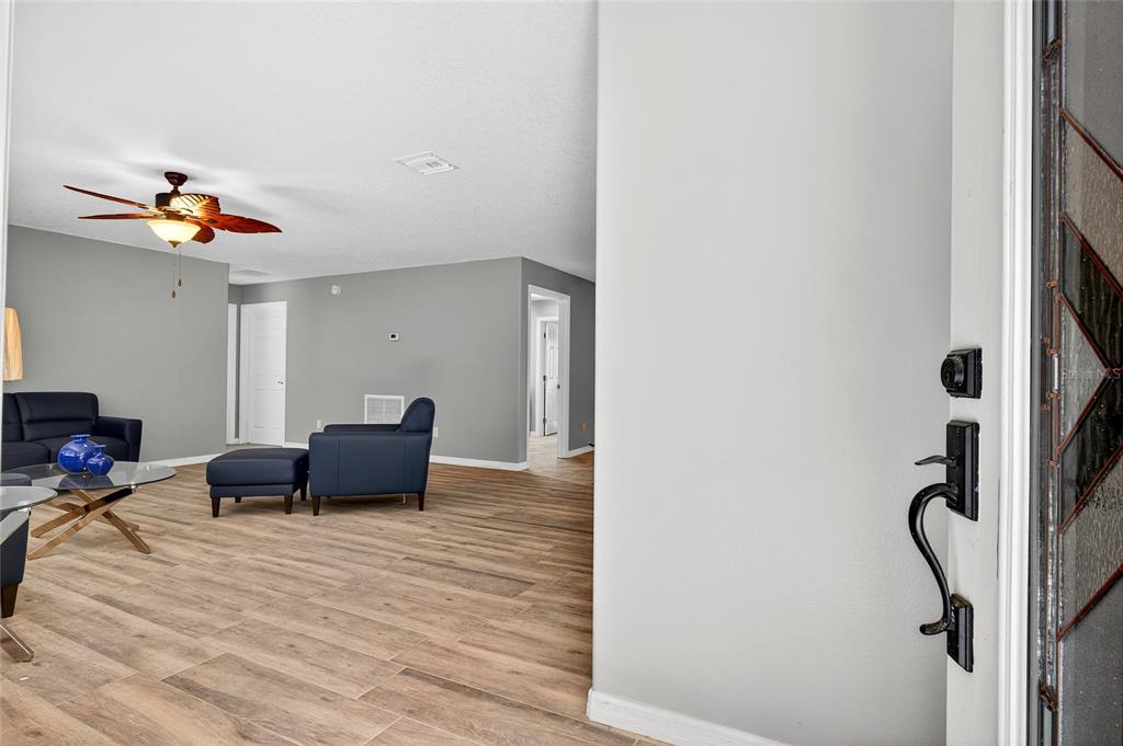 A view from an entryway into a living room with gray walls and wood-look flooring — 201 N WEST STREET, INTERLACHEN, FL