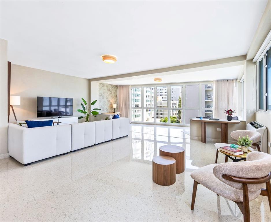 A bright living room features white sofas, a wooden coffee table, and large floor-to-ceiling windows — 57 ASHFORD AVENUE UNIT 5, SAN JUAN, PR