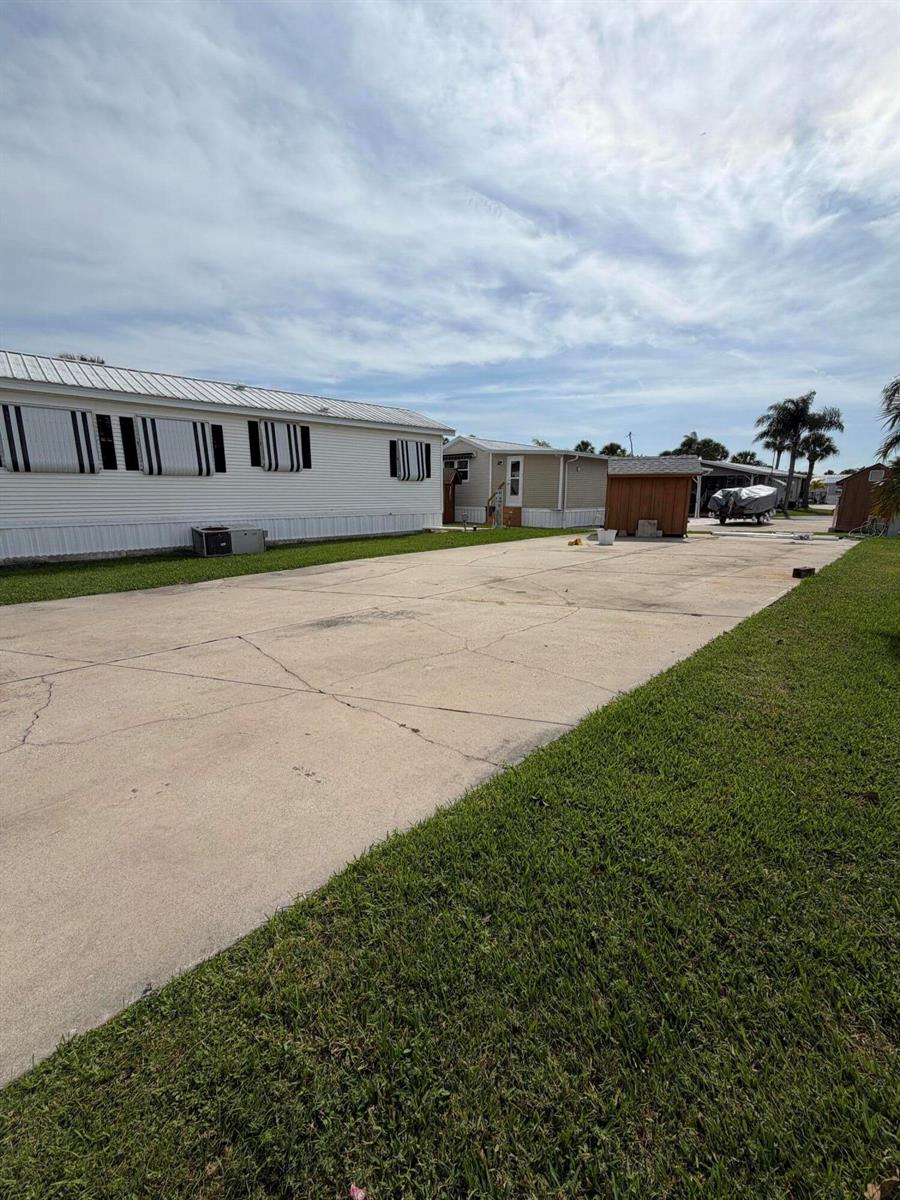 A large concrete driveway sits between two mobile homes under a cloudy sky — 5340 SE 65th Terrace, Okeechobee FL 34974, OKEECHOBEE, FL