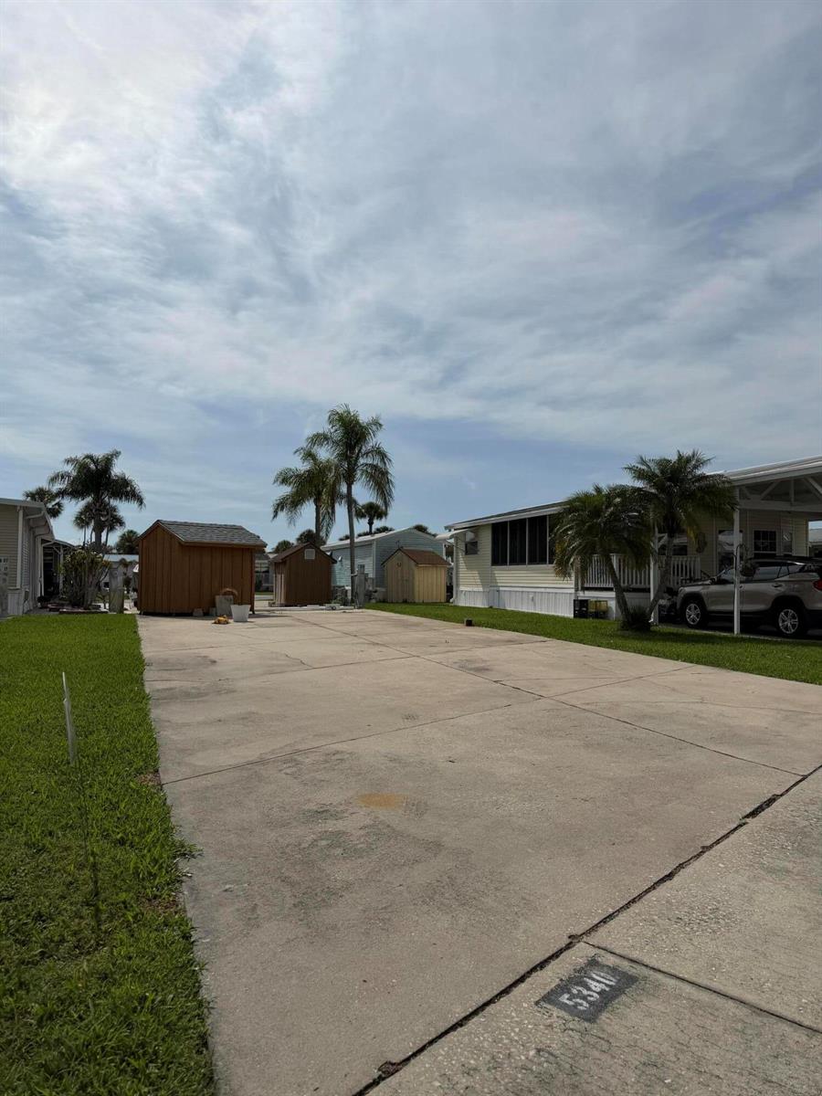 A concrete driveway leads toward three small storage sheds between two manufactured homes — 5340 SE 65th Terrace, Okeechobee FL 34974, OKEECHOBEE, FL