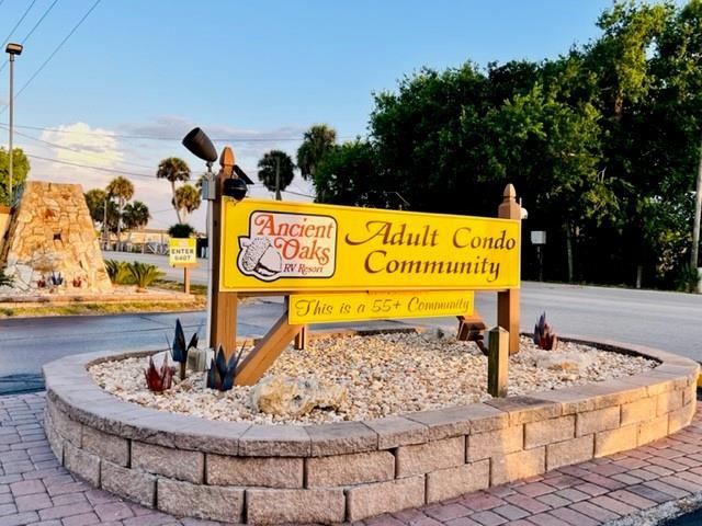 A yellow sign for Ancient Oaks RV Resort and Adult Condo Community sits in a planter — 5340 SE 65th Terrace, Okeechobee FL 34974, OKEECHOBEE, FL