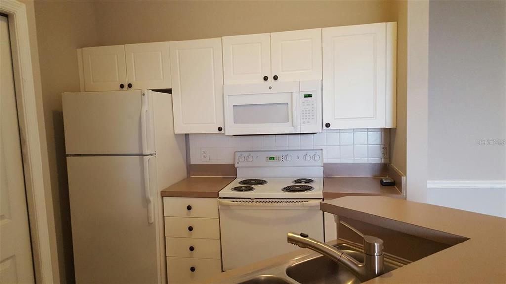 An interior view shows a carpeted living area, a kitchen counter, and a sliding glass door — 5168 NORTHRIDGE ROAD UNIT 311, SARASOTA, FL
