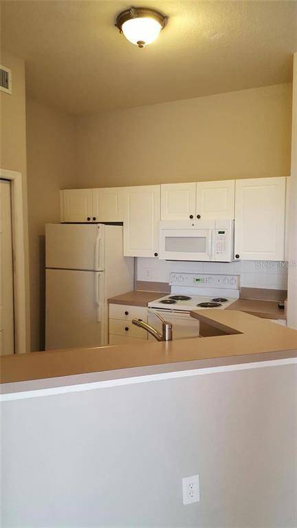 A kitchen features white cabinets, a white refrigerator, and a white electric range — 5168 NORTHRIDGE ROAD UNIT 311, SARASOTA, FL