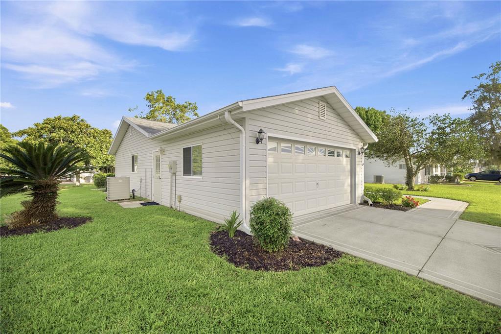 A light-colored house with a single-car garage and a concrete driveway on a grassy lawn — 17832 SE 96TH AVENUE, SUMMERFIELD, FL