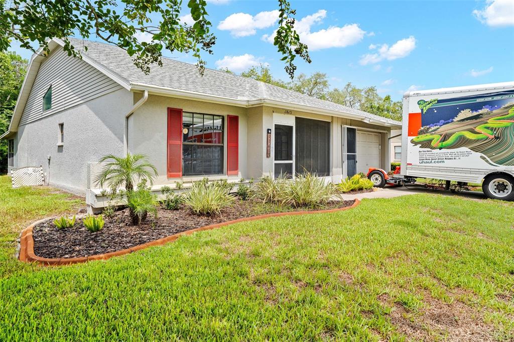 A single-story house with a U-Haul trailer parked in the driveway and a front garden — 11613 PEAR TREE DRIVE, NEW PORT RICHEY, FL