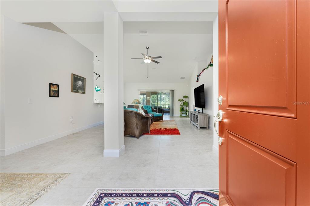 A red front door with sidelights and a transom window sits under a covered entryway — 133 MARINER LANE, ROTONDA WEST, FL