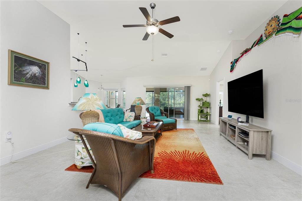 A view from an open orange front door into a bright living room with tile floors — 133 MARINER LANE, ROTONDA WEST, FL