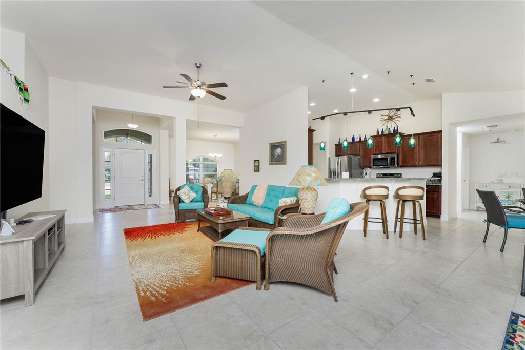 A living room features tile floors, a ceiling fan, a television, and wicker furniture — 133 MARINER LANE, ROTONDA WEST, FL
