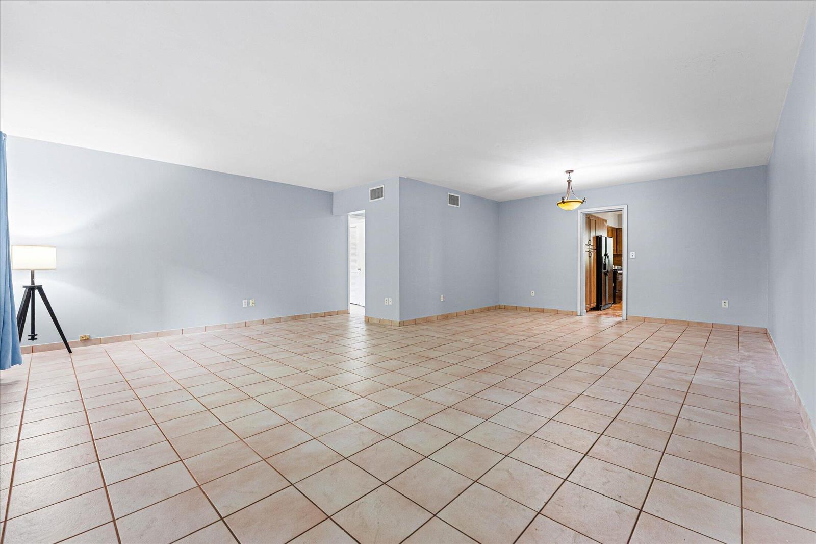 An empty room with light blue walls, beige tile flooring, and a tripod floor lamp — 1145 101 St # 1, Bay Harbor Islands FL 33154, BAY HARBOR ISLANDS, FL